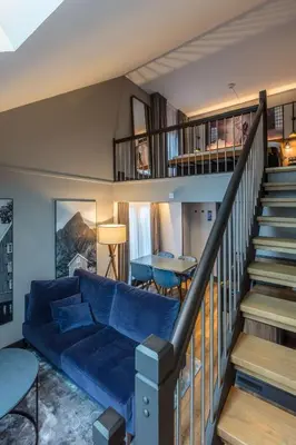 a living room with a blue couch and a staircase at Radisson Blu Royal Garden Hotel, Trondheim in Trondheim