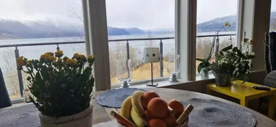 a table with a bowl of fruit in front of a window at Frydenlund in Balestrand