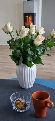 a white vase filled with white roses on a table at Frydenlund in Balestrand