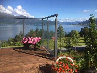 a deck with flowers and a view of a lake at Frydenlund in Balestrand