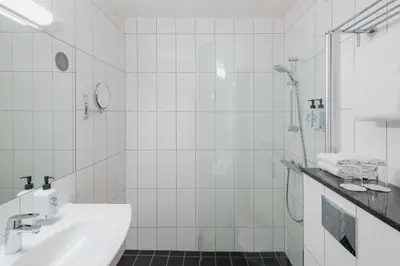 a white bathroom with a shower and a sink at Scandic Kokstad in Bergen