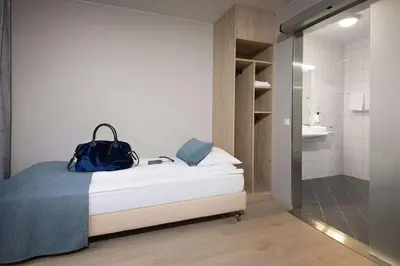 a bedroom with a bed with a blue bag on it at Scandic Kokstad in Bergen