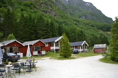 a group of cottages in the mountains with a table and chairs at Gudvangen Camping in Gudvangen