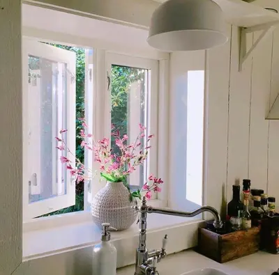 a kitchen sink with a vase of flowers in a window at The Boathouse in Råkvåg