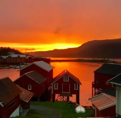 a sunset over a town with houses and a body of water at The Boathouse in Råkvåg