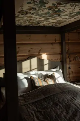 a bed with white pillows and a patterned ceiling at Storfjord Hotel in Skodje