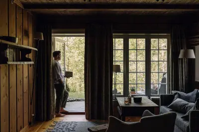 a man standing in a living room looking out the window at Storfjord Hotel in Skodje