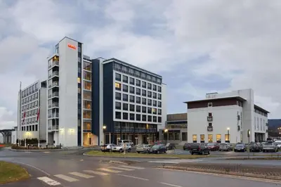a large building with cars parked in a parking lot at Scandic Hell in Hell