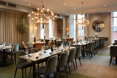a dining room with tables and chairs and chandeliers at Scandic Hell in Hell