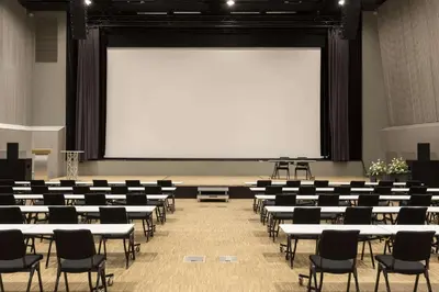 a classroom with tables and chairs and a large screen at Scandic Hell in Hell