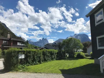 a house with a yard with mountains in the background at Åndalsnes Apartments - Luxury Stay in Åndalsnes