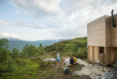 a group of people sitting on a hill near a building at Sommerhotellet in Vang I Valdres