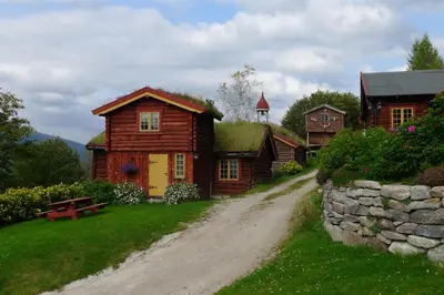 a house with a grass roof on a dirt road at Romenstad Hytter in Rendalen