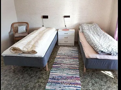 a bedroom with two beds and a chair and a rug at 8 person holiday home in EIDSVÅG in Eidsvåg