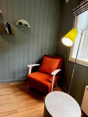 a room with a chair and a lamp and a table at Nes Gard in Høyheimsvik