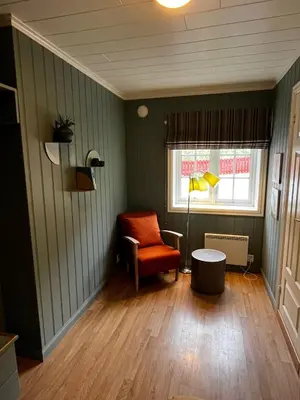 a living room with a chair and a window at Nes Gard in Høyheimsvik