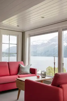 a living room with red furniture and a large window at Nes Gard in Høyheimsvik