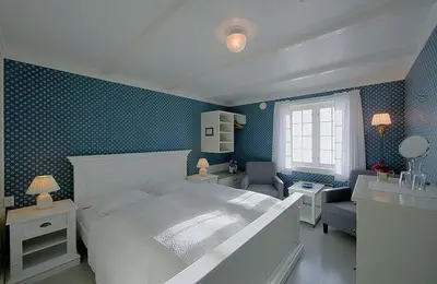 a bedroom with a white bed and a blue wall at Nes Gard in Høyheimsvik