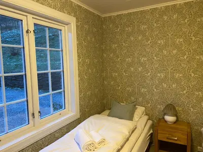 a small bedroom with a bed and a window at Nes Gard in Høyheimsvik