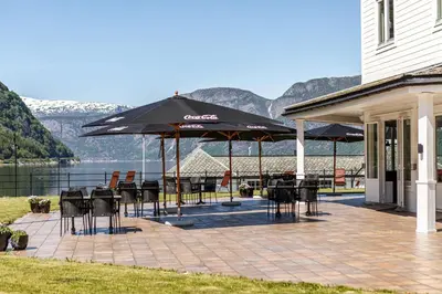 a patio with tables and chairs and umbrellas at Vøringfoss Hotel in Eidfjord