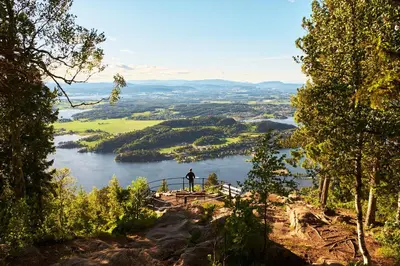 a man standing on a bridge overlooking a lake at Kleivstua Hotel near Krokskogen in Sundvollen