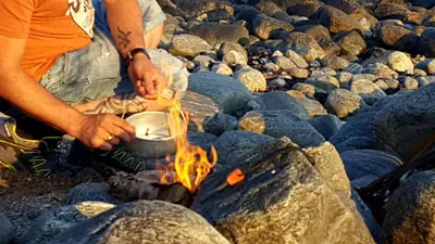two people cooking food in a pot over a fire at Kjørsvik Øvre in Tornes