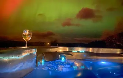 a glass of wine sitting on a table under the aurora at Amazing Home In Jøsenfjorden With Sauna in Gullingen