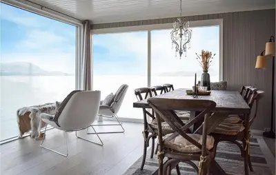 a dining room with a table and chairs and a large window at Lovely Home In Skånevik in Skånevik
