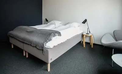 a bedroom with a bed and a lamp and a chair at Lindstrøm Hotel in Lærdalsøyri