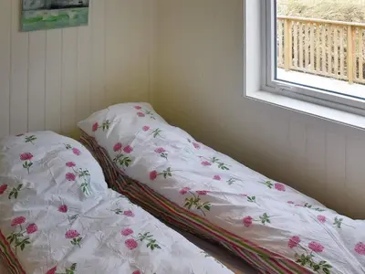 a bed with pink flowers on it in a room with a window at 10 person holiday home in Brattvåg in Brattvåg