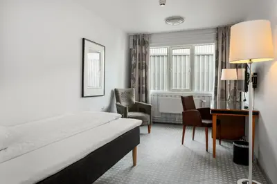 a hotel room with a bed and a desk and chairs at Frichs Hotel Hamar in Hamar