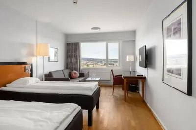 a hotel room with two beds and a living room at Frichs Hotel Hamar in Hamar