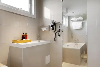 a white bathroom with a sink and a shower at Frichs Hotel Hamar in Hamar