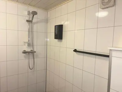 a shower in a white tiled bathroom at Winjum Apartments Aurland Stegastein in Aurland