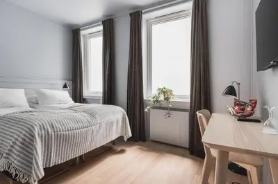 a bedroom with a bed and a desk and a window at Heimen Hotel in Bergen