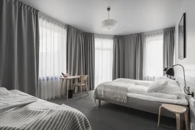 a bedroom with two beds and a table and windows at Heimen Hotel in Bergen