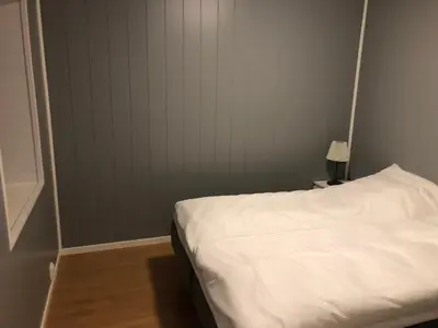 a bedroom with a white bed and a wall at Balestrand Fjordapartments in Balestrand