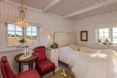 a bedroom with a bed and a table and a chair at Husfrua Gårdshotell in Straumen