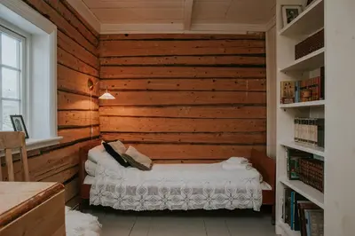 a room with a bed in a wooden wall at Husfrua Gårdshotell in Straumen