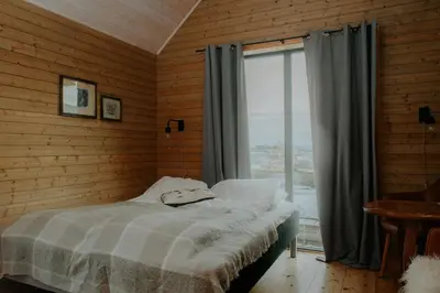 a bedroom with a bed and a large window at Husfrua Gårdshotell in Straumen