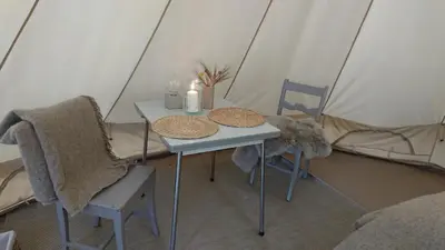 a table and two chairs in a tent at Husfrua Gårdshotell in Straumen