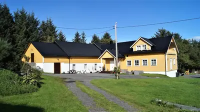 a large yellow house with a black roof at Vestavind hytter og rom AS in Ålesund