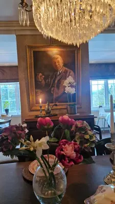 a table with flowers in front of a portrait of a man at Geilo Mountain Lodge in Geilo