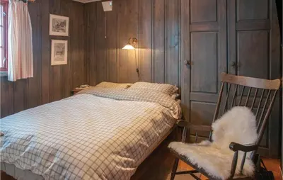 a bedroom with a bed and a rocking chair at Four-Bedroom Holiday Home In Rendalen in Rendalen