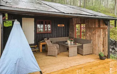 a patio with a table and wicker chairs on a wooden deck at Four-Bedroom Holiday Home In Rendalen in Rendalen
