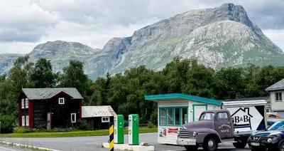 an old truck parked at a gas station in front of a mountain at Mjøsvang Kafe in Vang I Valdres