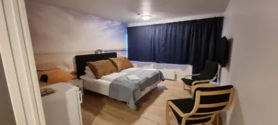 a room with a bed and a couch and chairs at Husnes Sentrum Hotell in Husnes