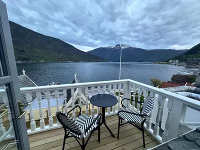 a table and chairs on a balcony with a view of the water at Hofslund Fjord Hotel in Sogndal