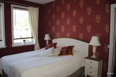 a bedroom with a white bed with red walls and a window at Nordfjord Hotell - Bryggen in Nordfjordeid