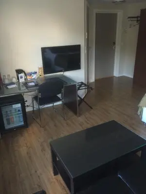 a living room with a television and a desk with a table at Nordfjord Hotell - Bryggen in Nordfjordeid